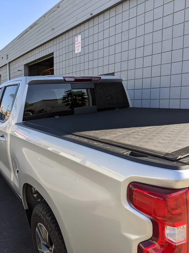 Silver Chevrolet Silverado with a soft roll-up tonneau cover pulled tight over the bed